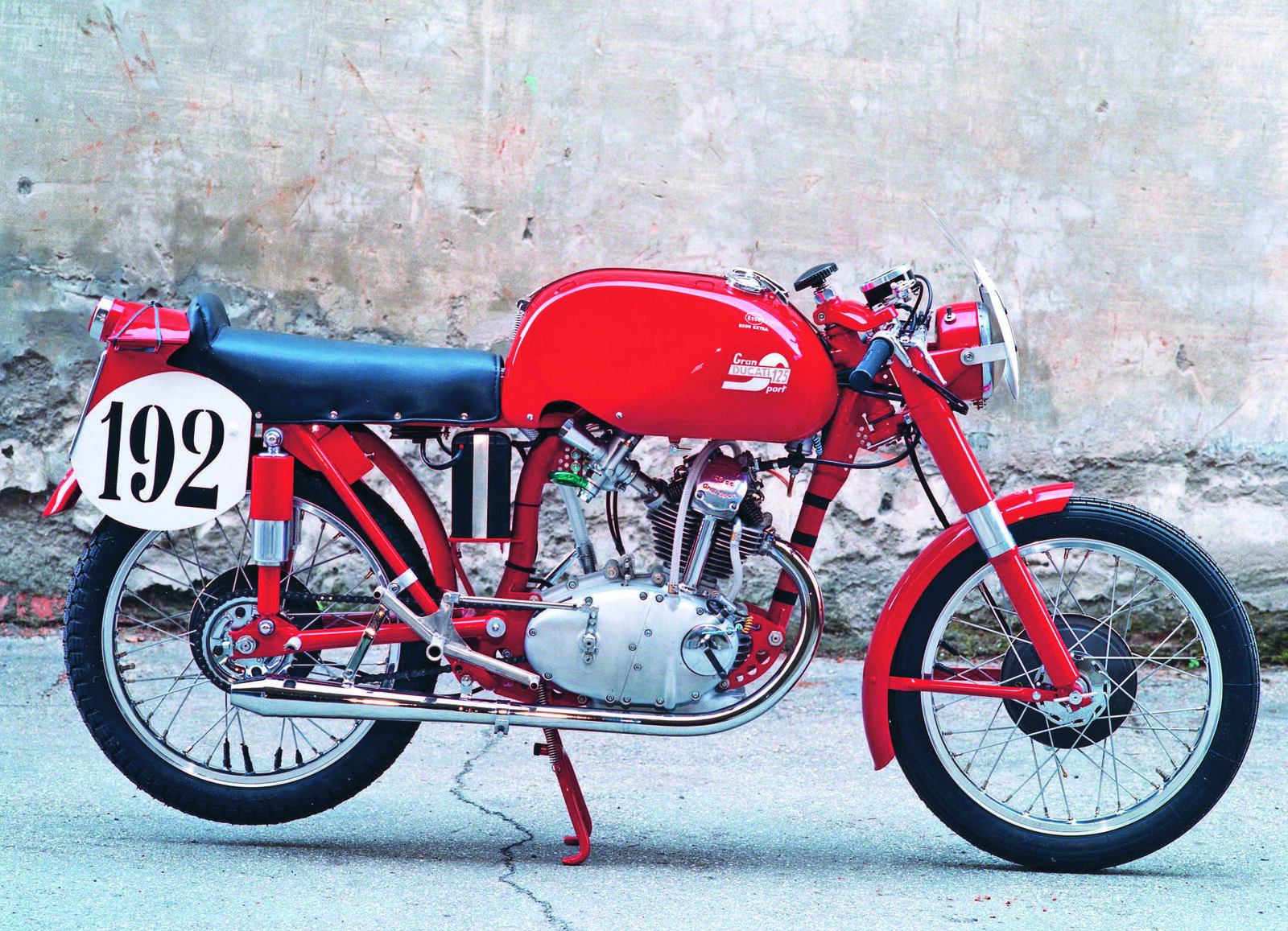A vintage red motorcycle, pictured on a simple background, with the number 192.