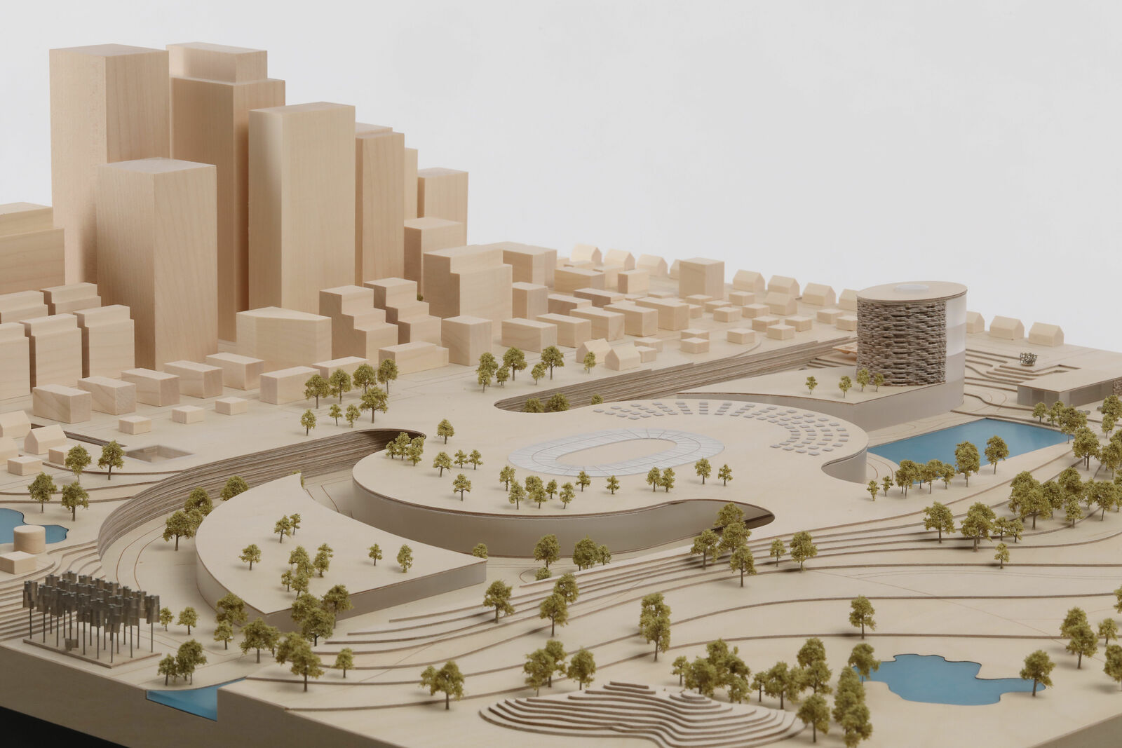 An architectural model of an urban landscape with modern buildings, parks, and water features. It depicts a detailed miniature of a city development.