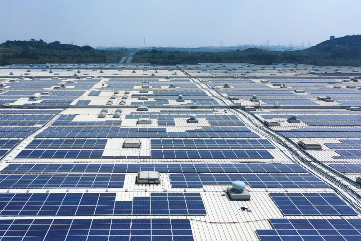 Expansive roof covered with solar panels, representing a sustainable energy source for an industrial facility.