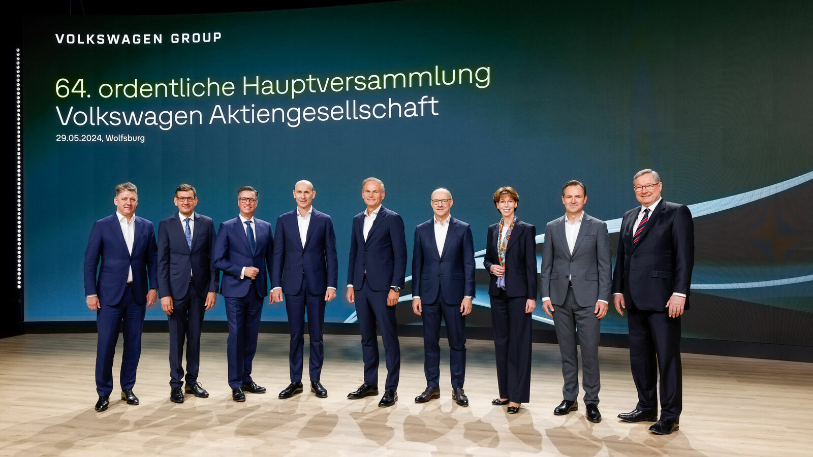 Group photo of eight people in suits on stage at the 64th ordinary general meeting of Volkswagen Aktiengesellschaft.