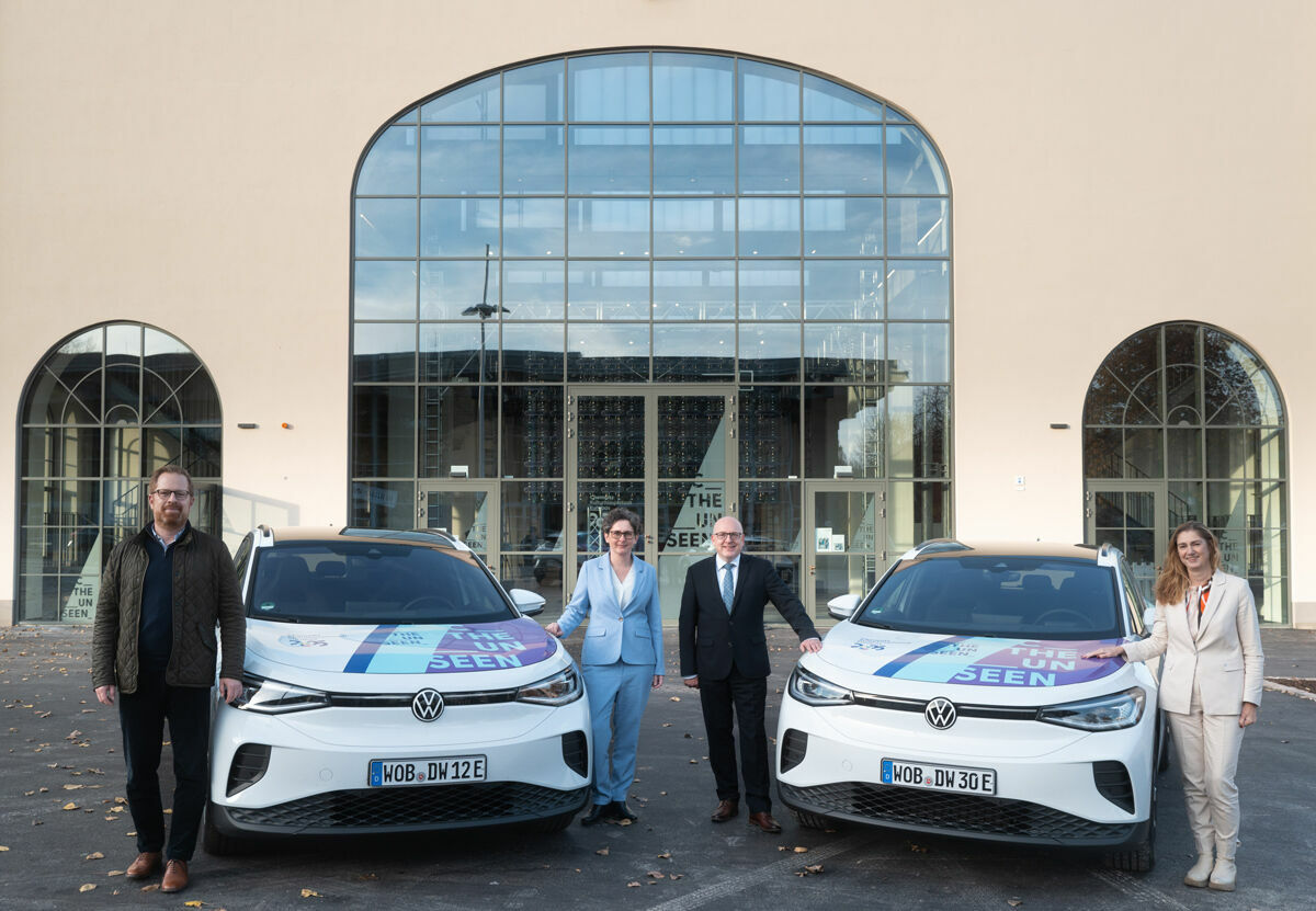 Group photo in front of the cultural center in Chemnitz with two Volkswagen ID.4 vehicles promoting the "The Unseen" campaign.