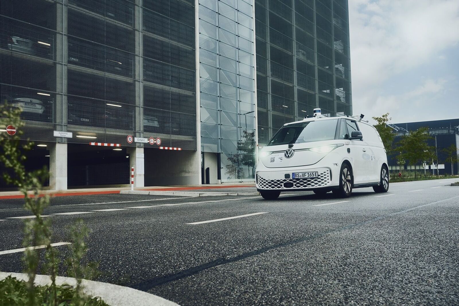 Self-driving VW van in front of a parking garage.